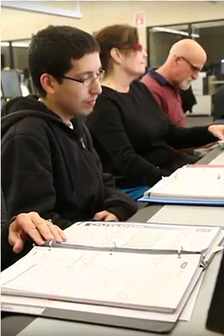 three students seated togther in classroom with notes - student